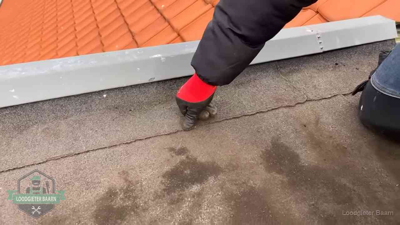 Lekkage bij de naad van een plat dak in Baarn Vakman wijst een naad met vochtplekken aan op een bitumen plat dak in Baarn