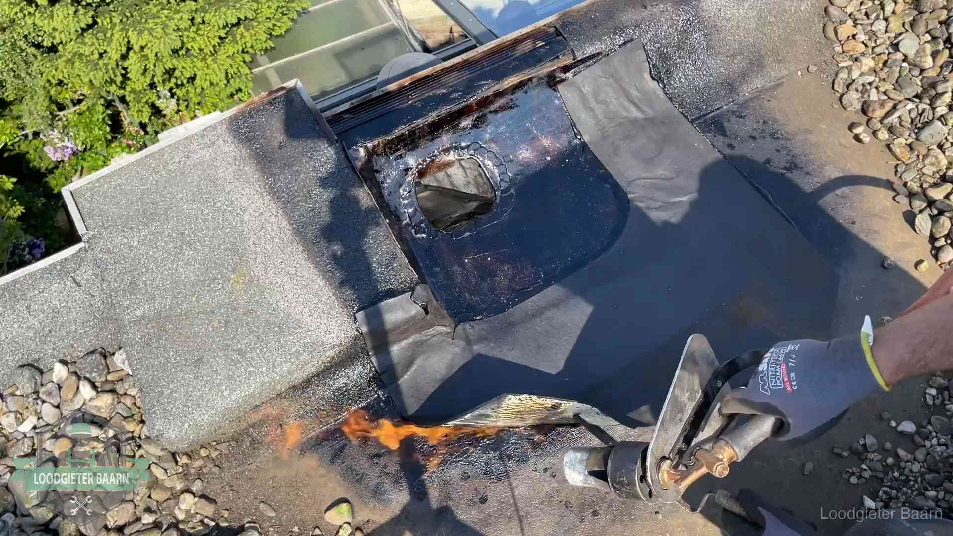 Daklekkage repareren in Baarn Dakdekker brandt bitumen rond een doorvoer tijdens een daklekkage-reparatie in Baarn