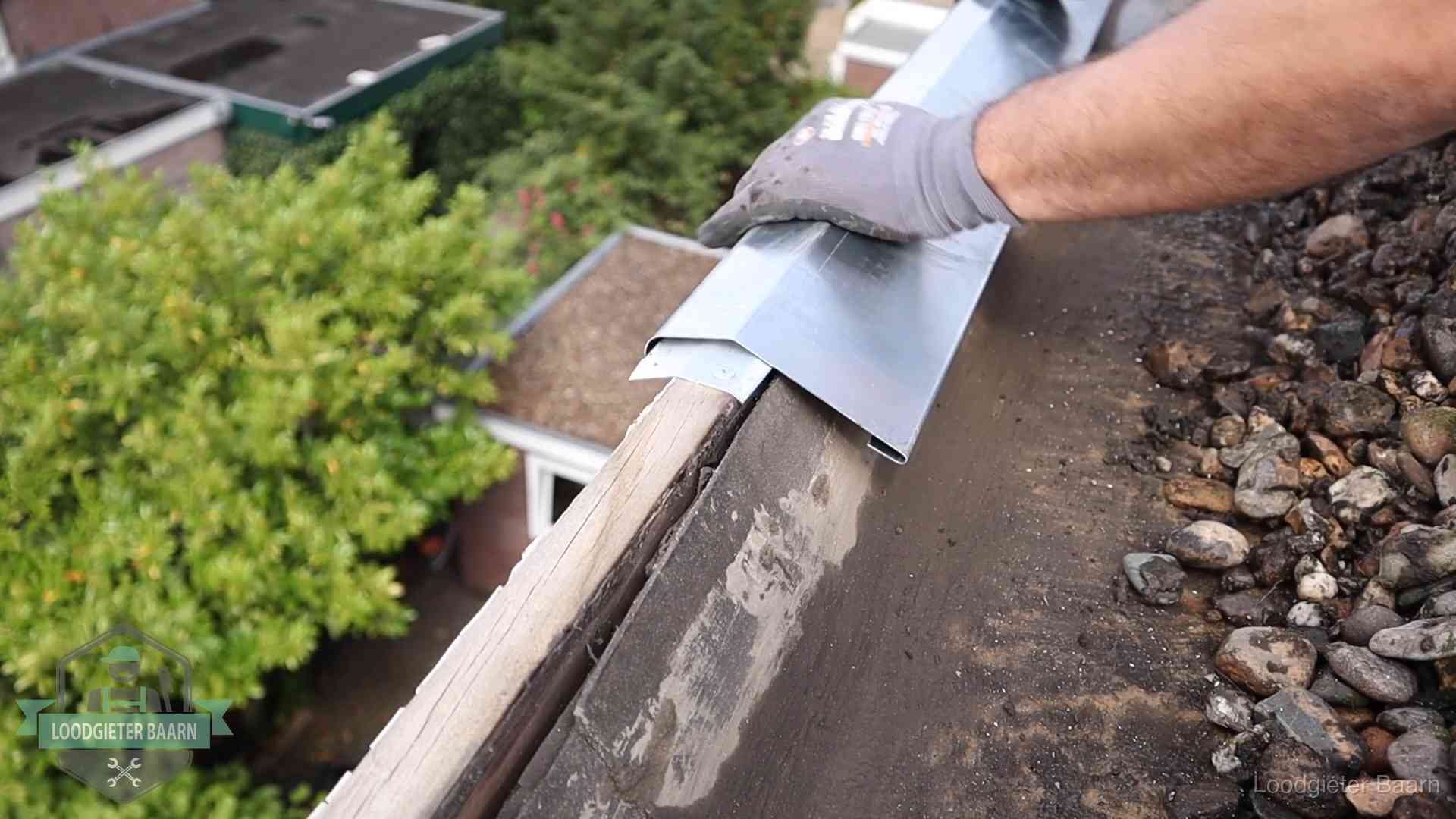 Daklekkage per wijk in Baarn Dakdekker plaatst een zinken deklijst op een dakrand met uitzicht over een woonwijk in Baarn