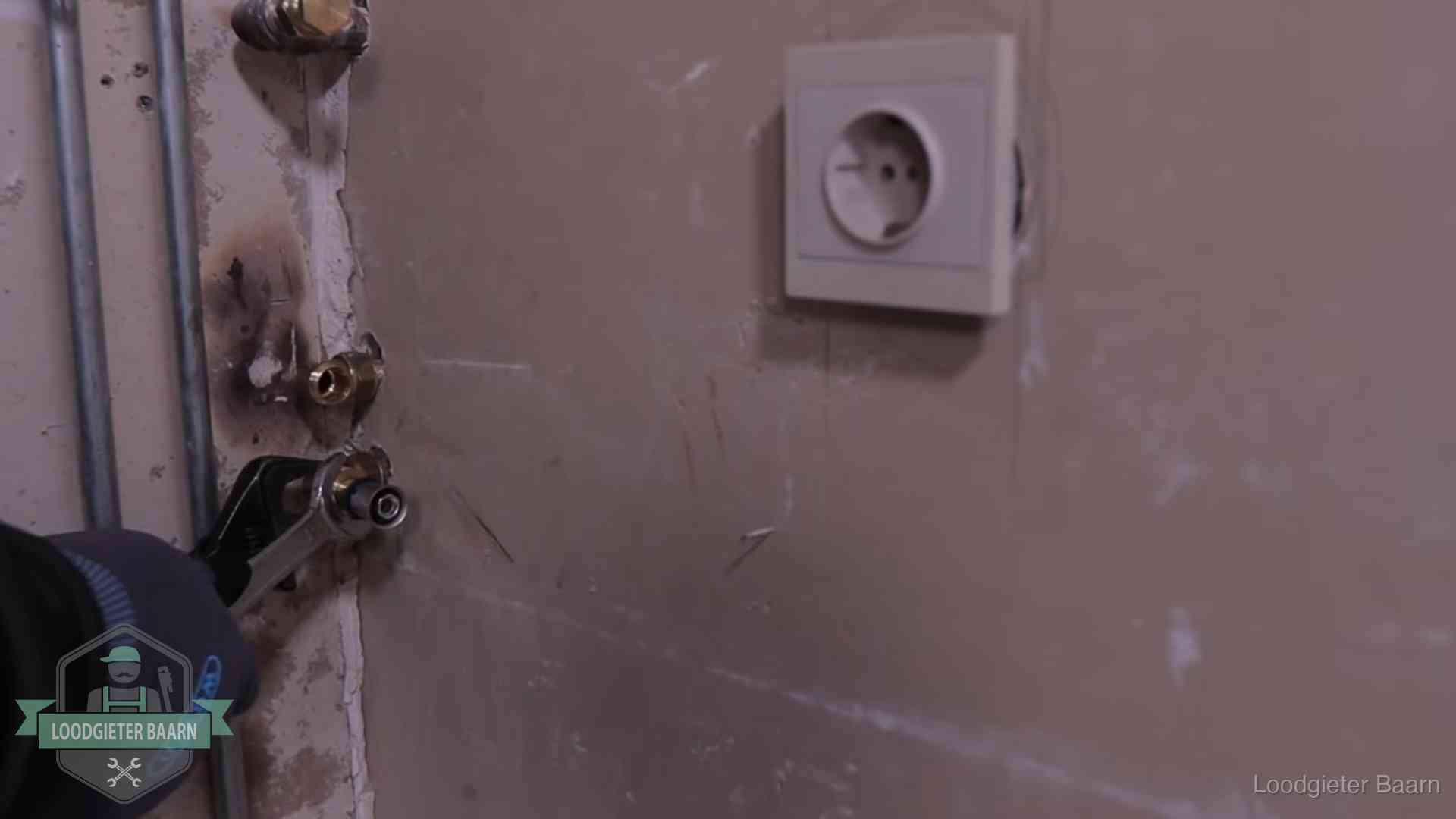 Monteur draait een perskoppeling vast op een leidingaansluiting in Baarn