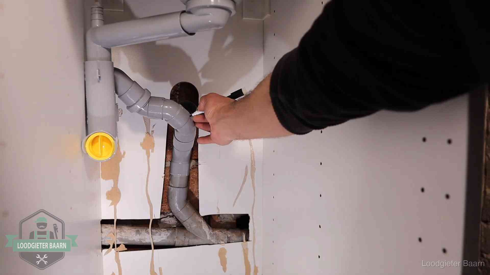 Loodgieter markeert een pvc-afvoerbuis onder een gootsteen in Baarn