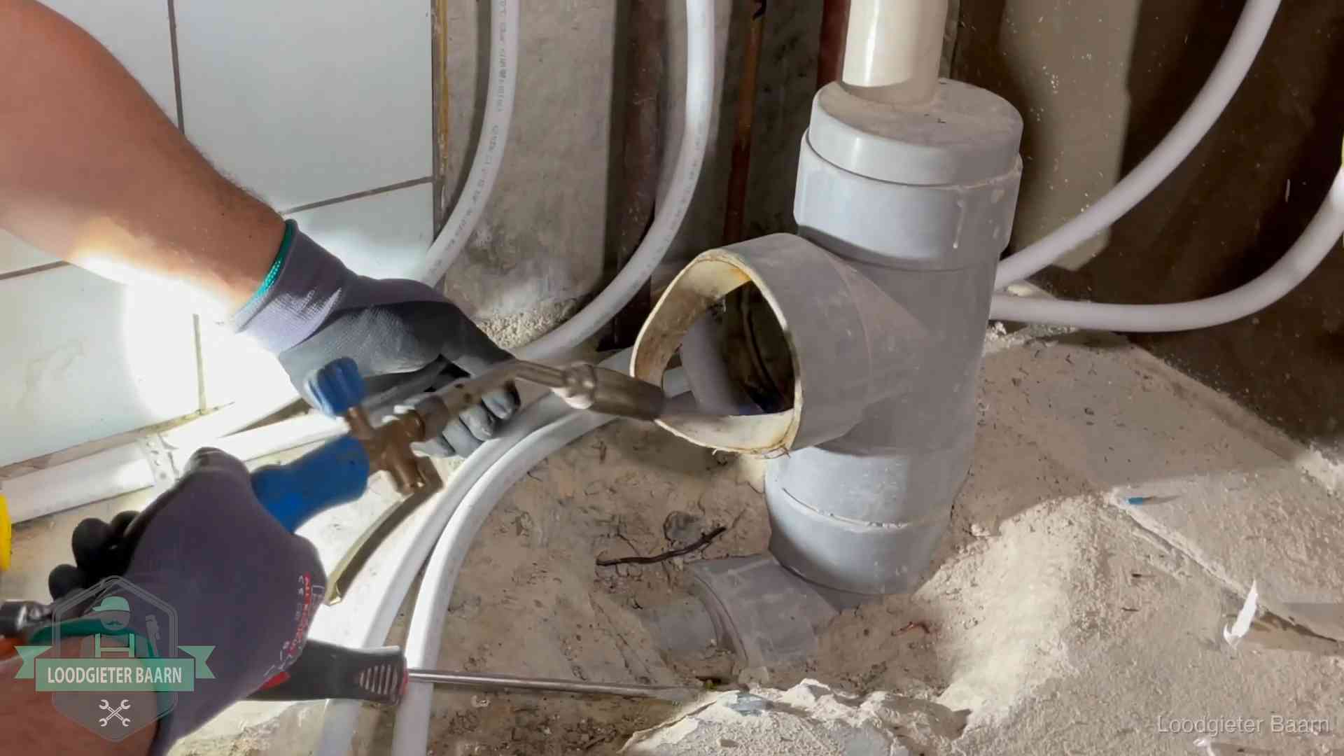 Loodgieter werkt met brander en messing kraanwerk aan leidingen in Baarn