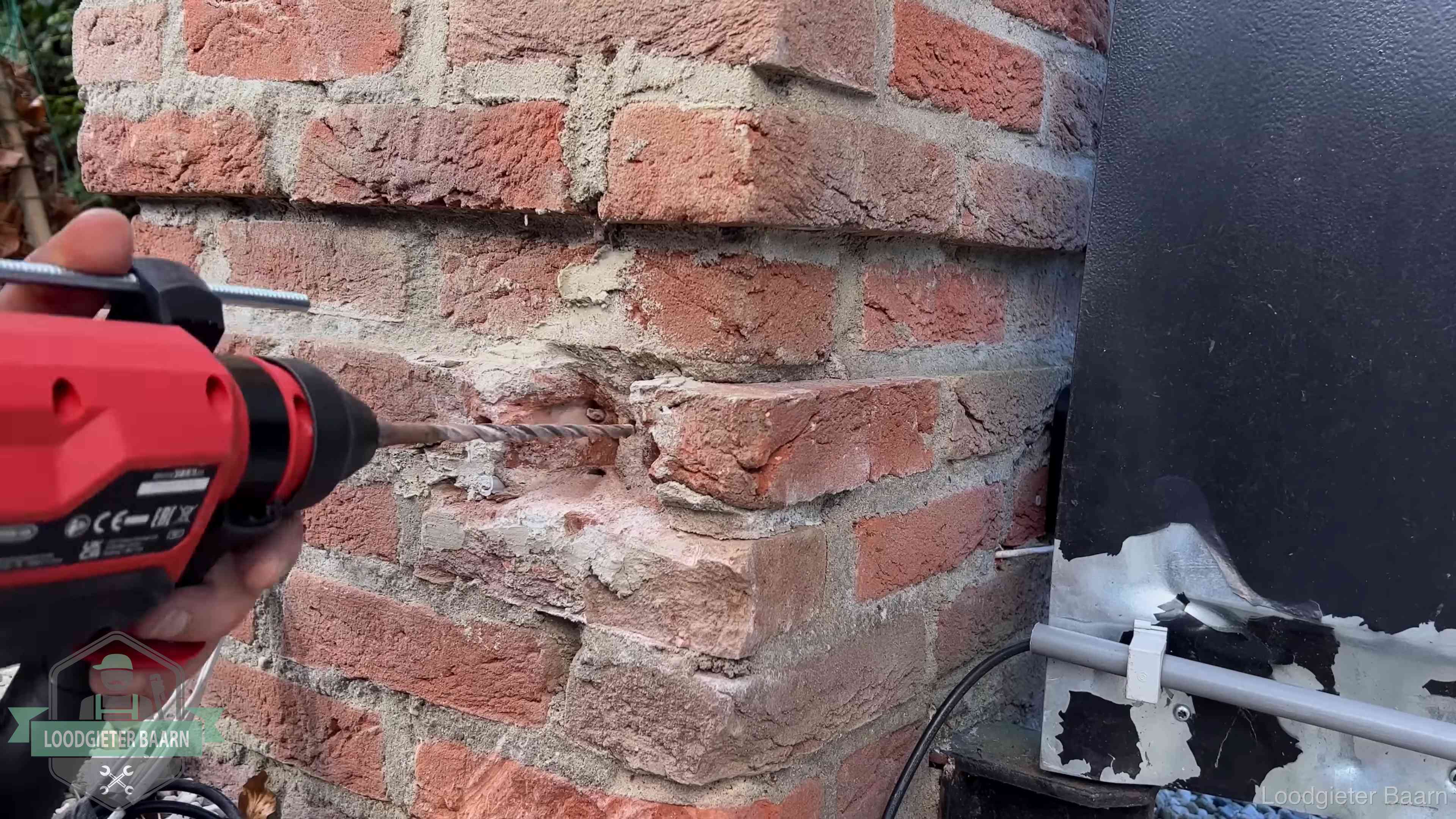 Vakman boort in de buitenmuur van een woning in de regio Baarn