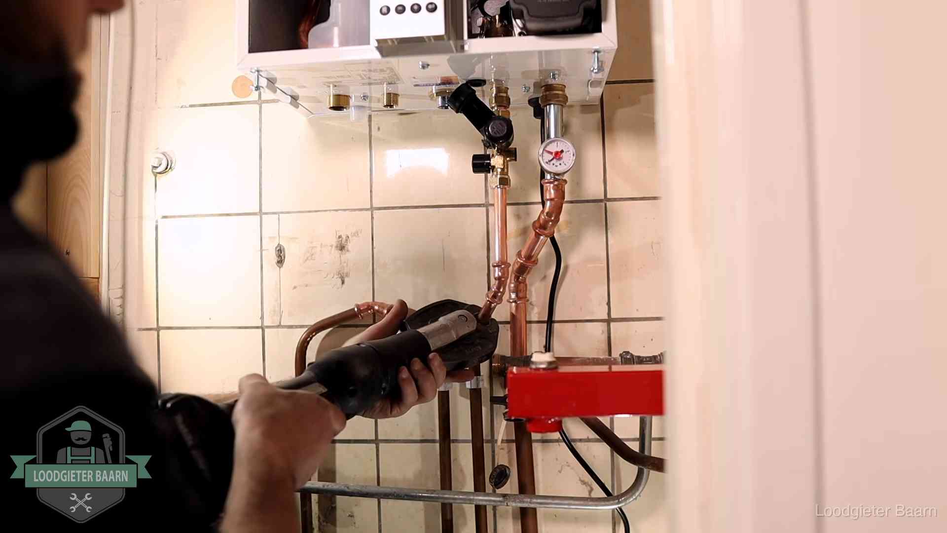 Monteur werkt aan de leidingen onder een cv-ketel in Baarn
