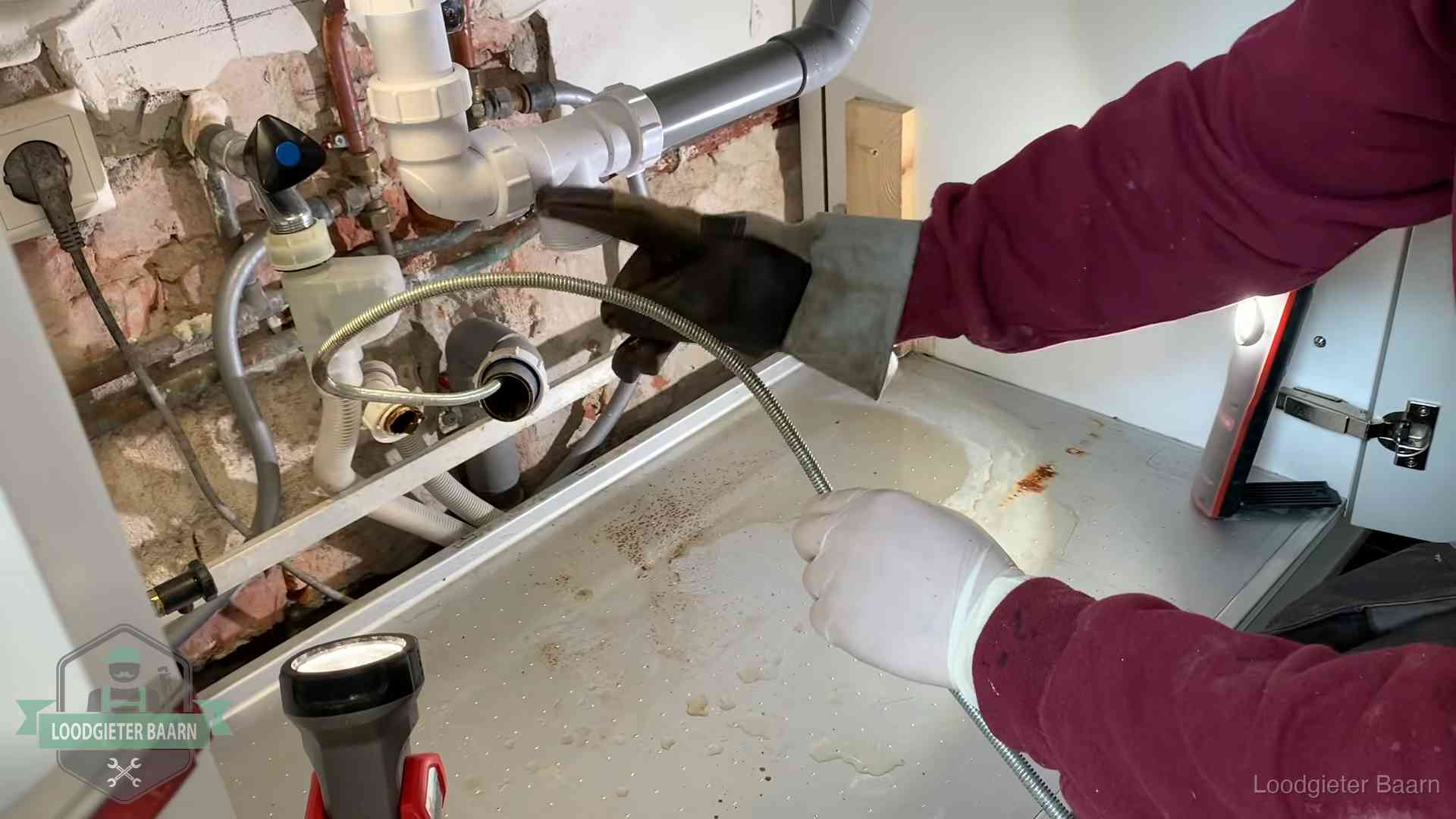 Spiraal of hogedruk in Baarn Ontstoppingsveer gaat in een geopende sifonaansluiting onder het aanrecht in Baarn