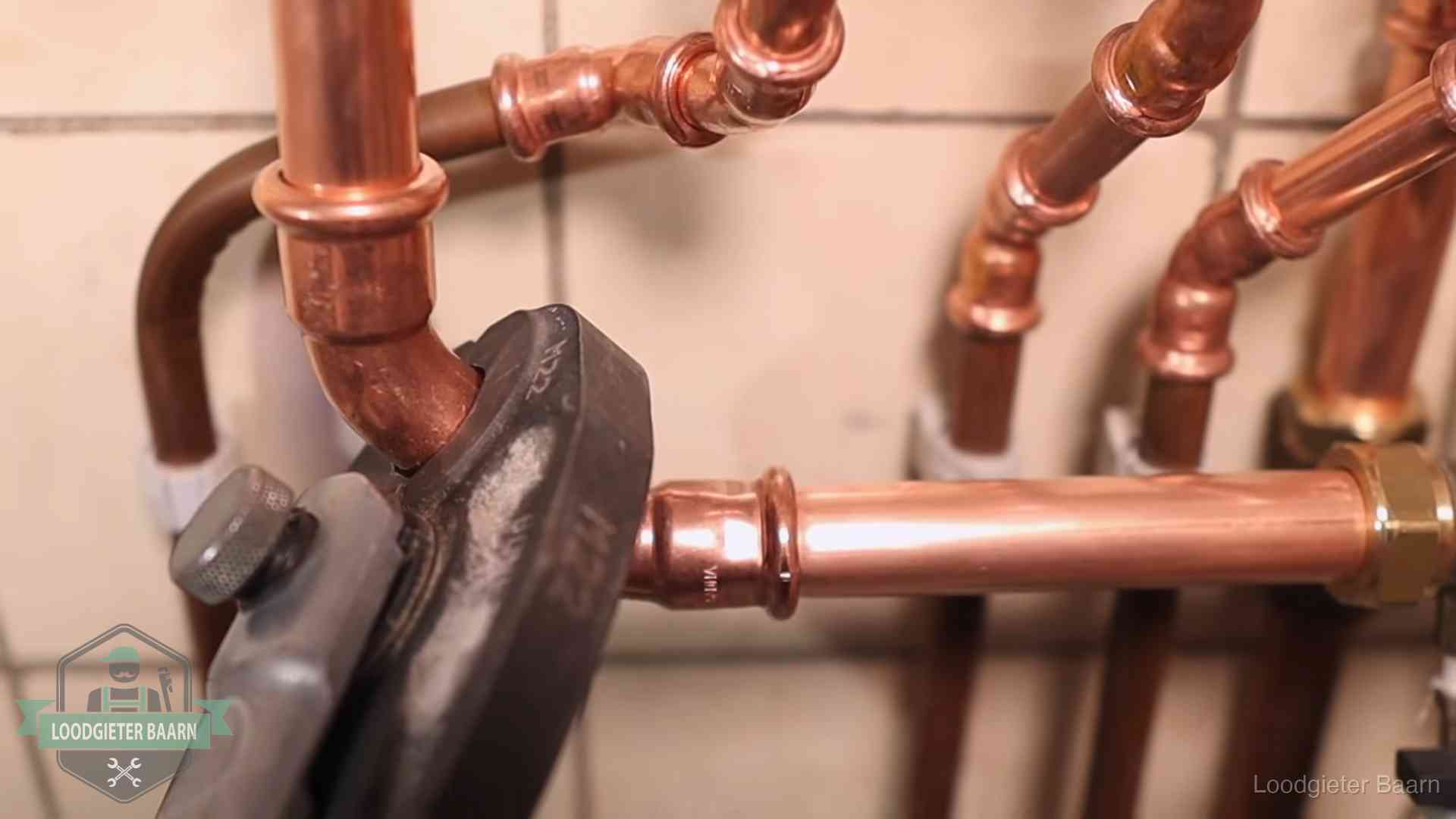 Persmachine perst een koperen fitting op nieuw leidingwerk in Baarn