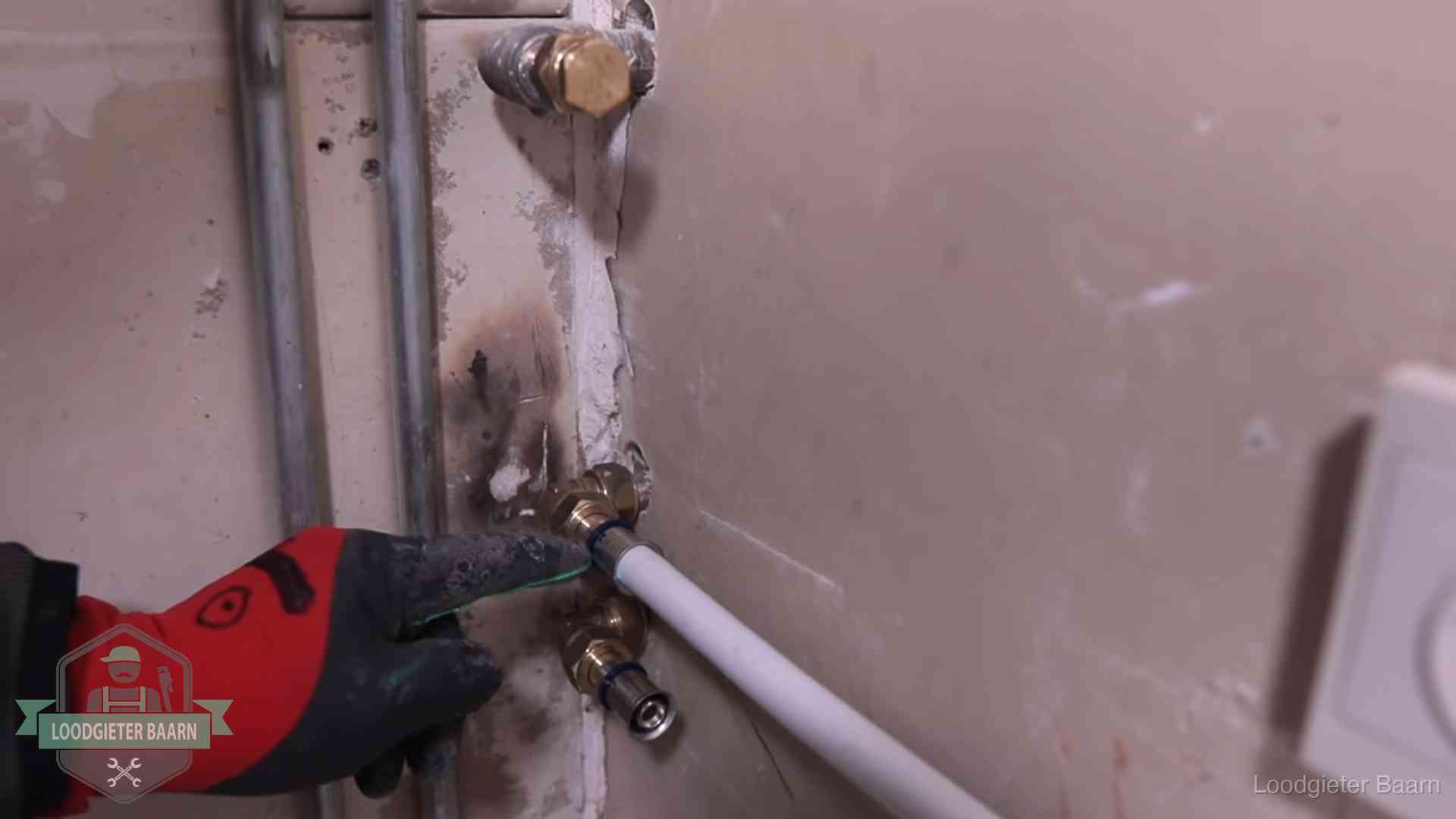Loodgieter wijst de persfitting op nieuwe muuraansluitingen aan in een woning in Baarn