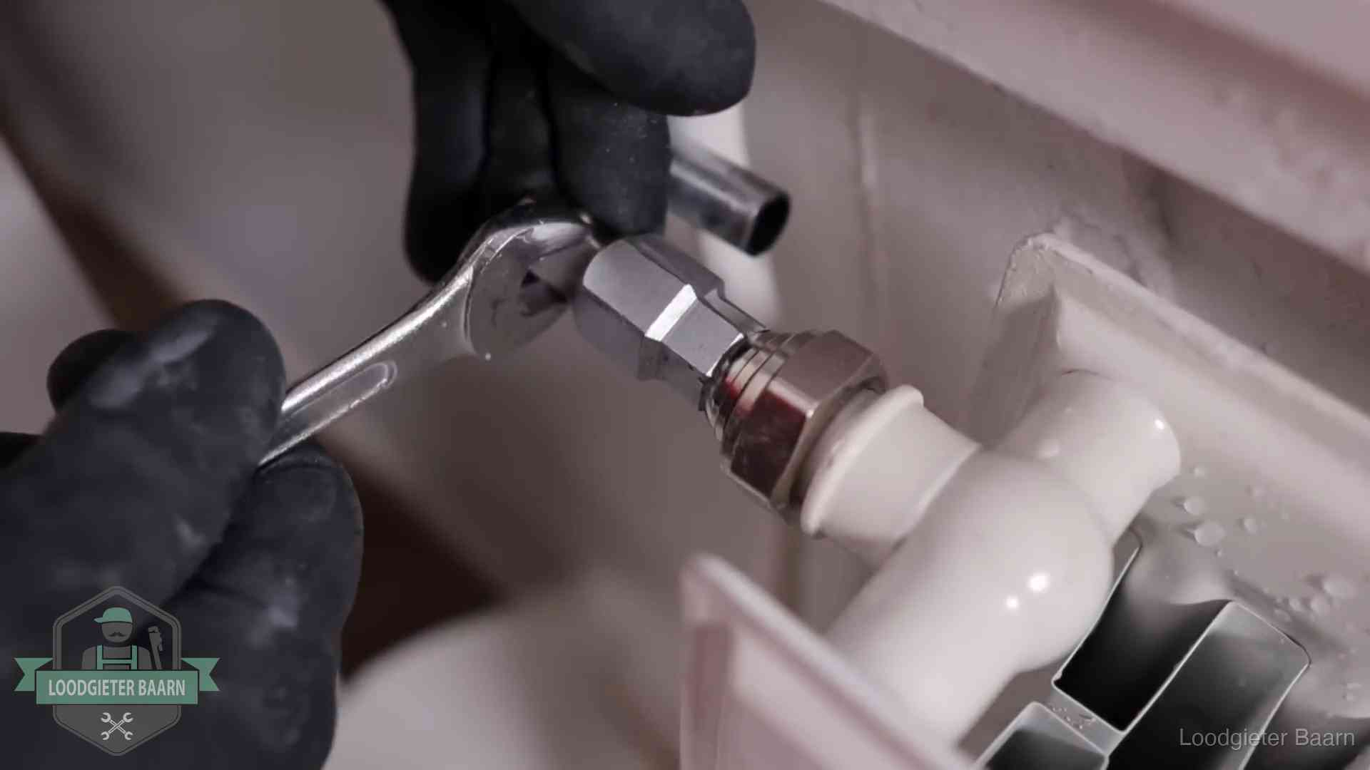 Steeksleutel draait een wartelkoppeling op een radiatorkraan aan in Baarn