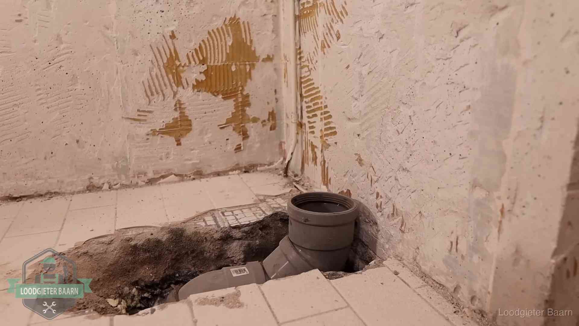 Verzakt riool herstellen in Baarn Opengebroken vloer met een nieuwe pvc-rioolbocht in een gegraven sleuf in Baarn