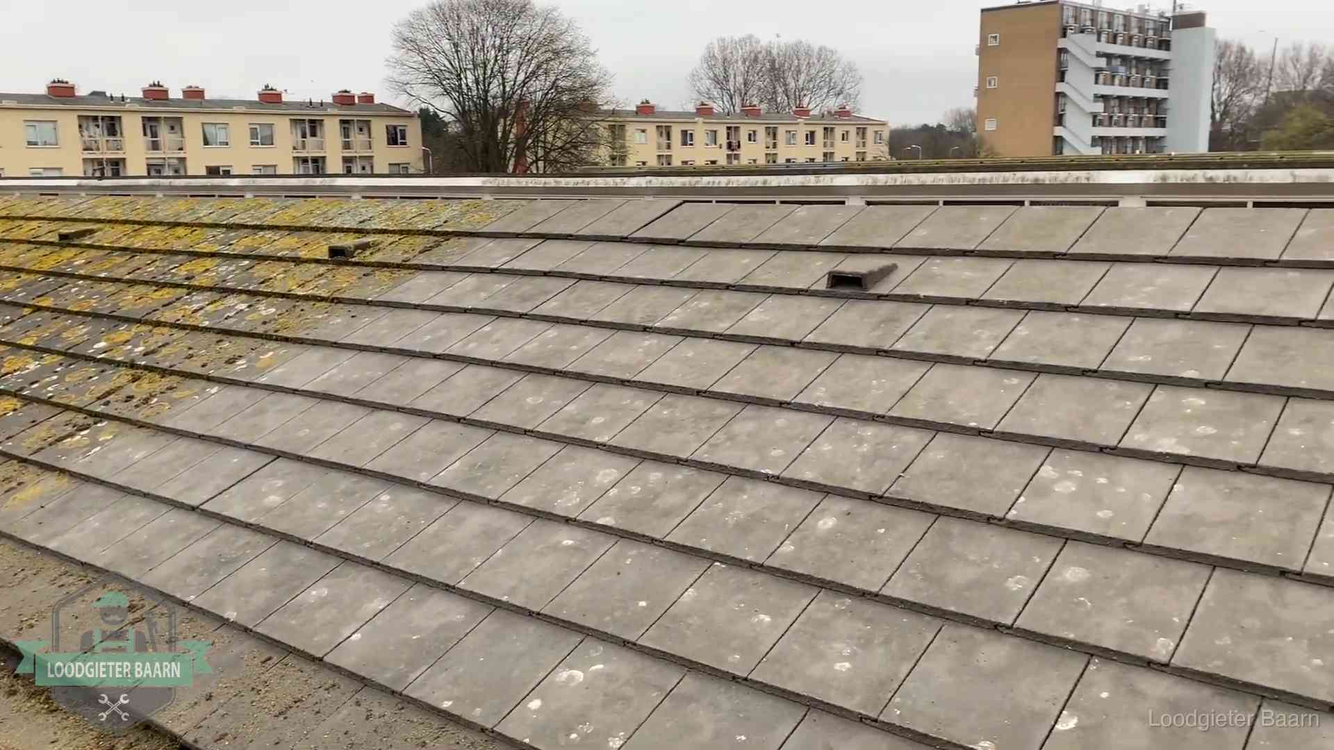 Dakpannen op een schuin dak in Baarn Schuin dak met betonpannen vol mos in Baarn, een risico op lekkage bij de pannen