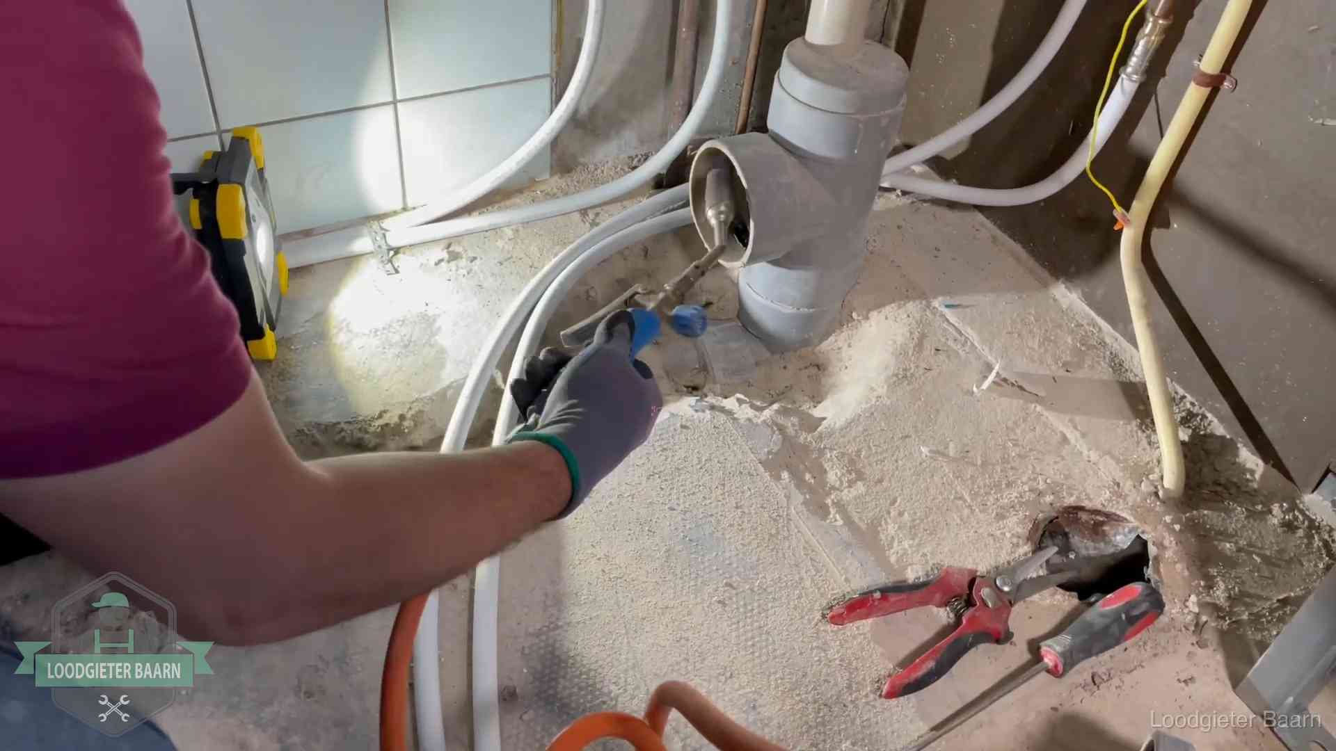 Loodgieter werkt aan leidingen bij een pvc-standleiding in een appartement in Baarn